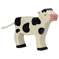 Veau noir et blanc debout Holztiger